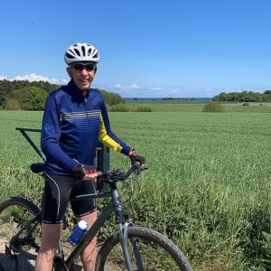 a man standing next to a bike in a field at Sommerliv Bed and Breakfast in Tranekær