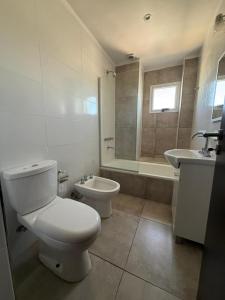 a white bathroom with a toilet and a sink at Altostay in Villa Constitución