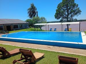 a swimming pool with two chairs and a house at Paraíso Yapeyu in Yapeyú