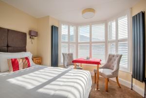 a bedroom with a bed and two chairs and a red table at Potters Mooring Guest House in Teignmouth