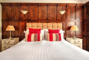 a bedroom with a large bed with red and white pillows at Potters Mooring Guest House in Teignmouth
