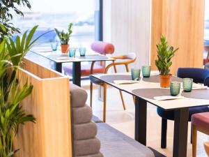 a row of tables in a restaurant with plants at Mercure Bucharest Cantemir in Bucharest