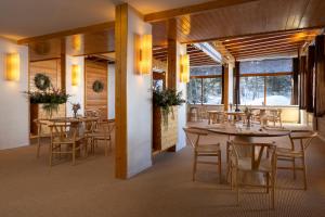 a dining room with tables and chairs and windows at Crystal Hôtel in Courchevel
