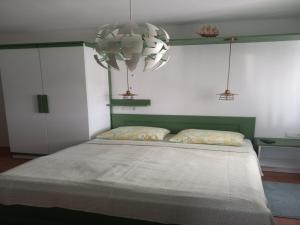 a bedroom with a large bed with a chandelier at Guest House Green Corner Supetarska Draga in Supetarska Draga