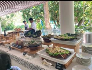 two people standing at a buffet table with food at Tambuli Seaside Living Condominium -Private Host Tower D in Maribago