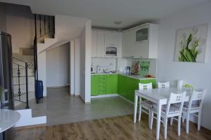 a kitchen with green cabinets and a white table and chairs at Large Two Floor Apartment in Byala
