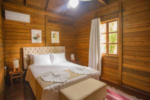 a bedroom with a bed with wooden walls and a window at Pousada Fazenda Caetés in Camboriú
