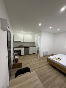 a white room with a bed and a kitchen at STUDIO deux NEUF A CROSNE in Crosne