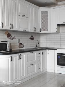 a white kitchen with white cabinets and appliances at высотка 15 in Aktobe +7 photos