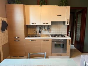 a kitchen with wooden cabinets and a stove top oven at Pegaso - bilocale a pochi passi dal centro in Pordenone +7 photos