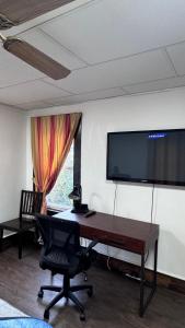 a desk with a chair and a television on a wall at Private 1BR Near Boston -- Kitchen & Laundry in Malden