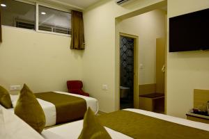 a hotel room with two beds and a flat screen tv at SR Grand in Tumkūr