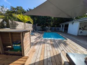 a swimming pool on a wooden deck with an umbrella at Gîtes l'orée Bleue in Sainte-Rose