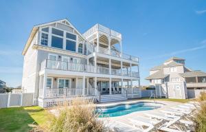 a large white house with a swimming pool and chairs at Frankly My Dear - Duck, Oceanfront, Elevator, Wheelchair Friendly, Pool Table, Pool, Hot Tub, Flex Stays in Duck