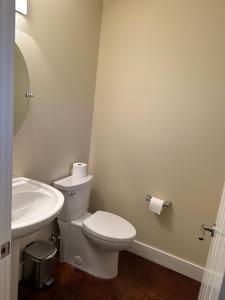a white bathroom with a toilet and a sink at Large ocean view family retreat in Comox