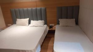 two beds in a room with white sheets and pillows at Hotel Dreamland in Malsiān Shāhkot