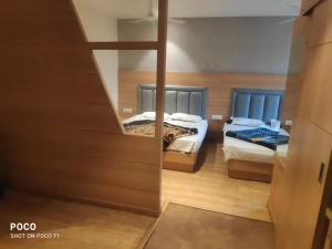 a bedroom with two beds and a mirror at Hotel Dreamland in Malsiān Shāhkot