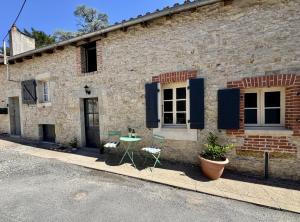 a brick building with blue shuttered windows and a table at La Maison de Lyon in Saint-Laurent-de-Céris