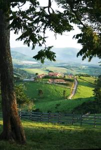 a green hill with a tree and a fence at Chalé Romântico in Extrema