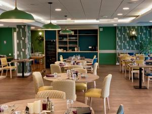 a restaurant with tables and chairs and green walls at Domitys Les Clés d'Or in Orthez