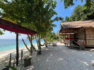 a beach with a hut and the ocean at Frits Homestay in Kri