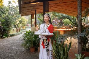 a woman in a dress holding a tray of food at Green Mansions Jungle Resort in Sauraha