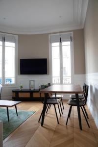 a living room with a table and chairs and a flat screen tv at Au bonheur de Troyes in Troyes