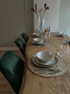 a wooden table with plates and wine glasses on it at Maastricht House Anne in Maastricht