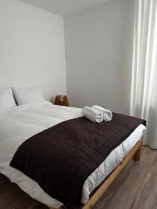 a bed with a black blanket and two towels on it at Maastricht House Anne in Maastricht