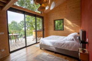 a bedroom with a bed and a balcony with a table at Les Coteaux - Lodges & Expériences in Laparade
