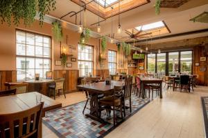 a restaurant with tables and chairs and windows at Brewhouse & Kitchen - Bournemouth - Southbourne in Bournemouth