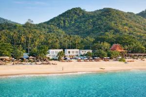 a beach with people sitting on the sand and the water at Sela Lanta in Ko Lanta