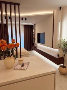 a living room with a television and a table with flowers at Mediteran Line Apartman 1 in Sombor