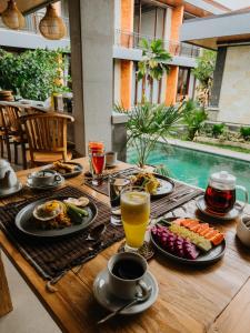 a table with breakfast foods and drinks on it at Koeluma Bali in Ubud