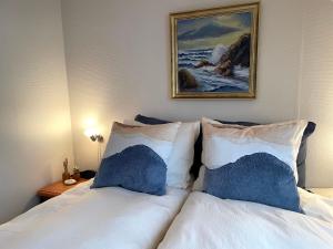 a white bed with blue pillows and a painting on the wall at Nygaard B&B in Nørre Nebel