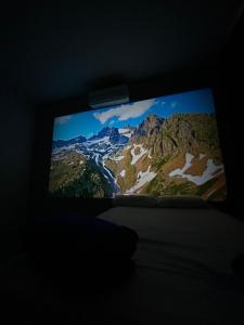 a television screen in a dark room with a mountain at Garden Room Comfort in Garanhuns