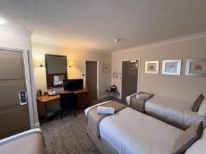 a hotel room with two beds and a desk at Caledonian Hotel in Newcastle upon Tyne