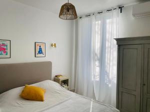 a bedroom with a bed with a yellow pillow and a window at Gîte Mas La Bohème Piscine Parking Privé L'Isle-Sur-La-Sorgue in L'Isle-sur-la-Sorgue +14 photos