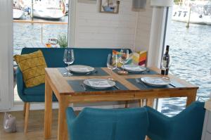 a wooden table with wine glasses and blue chairs at Hausboot Hecht mit Dachterrasse in Schleswig in Schleswig +10 photos