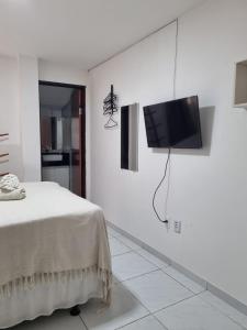 a white room with a bed and a television on a wall at Pousada Espaco Luz do Sol Beira-Mar in João Pessoa