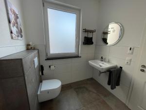 a bathroom with a toilet and a sink and a window at Villa Kunterbunt in Bad Staffelstein