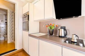 a kitchen with white cabinets and flowers in a vase on the counter at Fuga romantica - Mansarda chic con box privato & mare a 150m in Loano