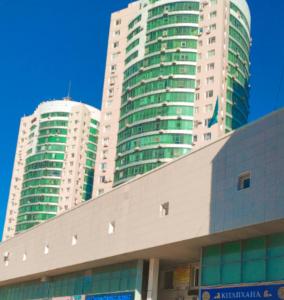 two tall buildings are in the background of a building at высотка 15 in Aktobe