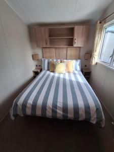 a bedroom with a blue and white striped bed at Beachside Heacham in Heacham
