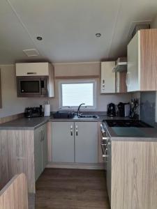 a small kitchen with white cabinets and a sink at Beachside Heacham in Heacham +8 photos