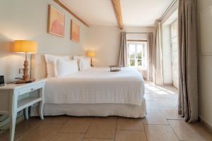 a bedroom with a white bed and a window at Coquillade Provence - Relais & Châteaux in Gargas +54 photos