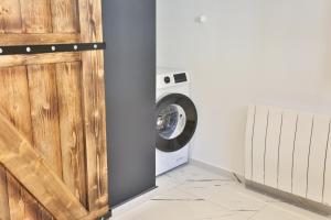 a laundry room with a washing machine and a wooden door at Le Speakeasy - Maison avec billard in Auxerre