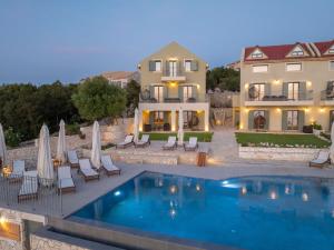 a pool in front of a house with chairs and umbrellas at Hellosummer Boutique suites,near fiscardo! in Andipáta Erísou