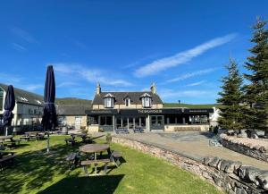 a building with a picnic table in the grass at The Balavoulin - Pub with Rooms in Aviemore