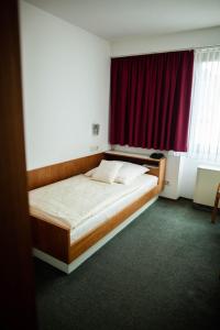 a bed in a room with a red window at Hotel-Cafe Römer in Siegen